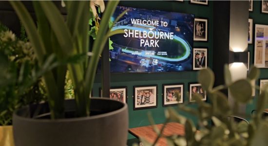 Image shows a screen in the new Food Hall welcoming you to Shelbourne Park with photographs surrounding it and lush greenery